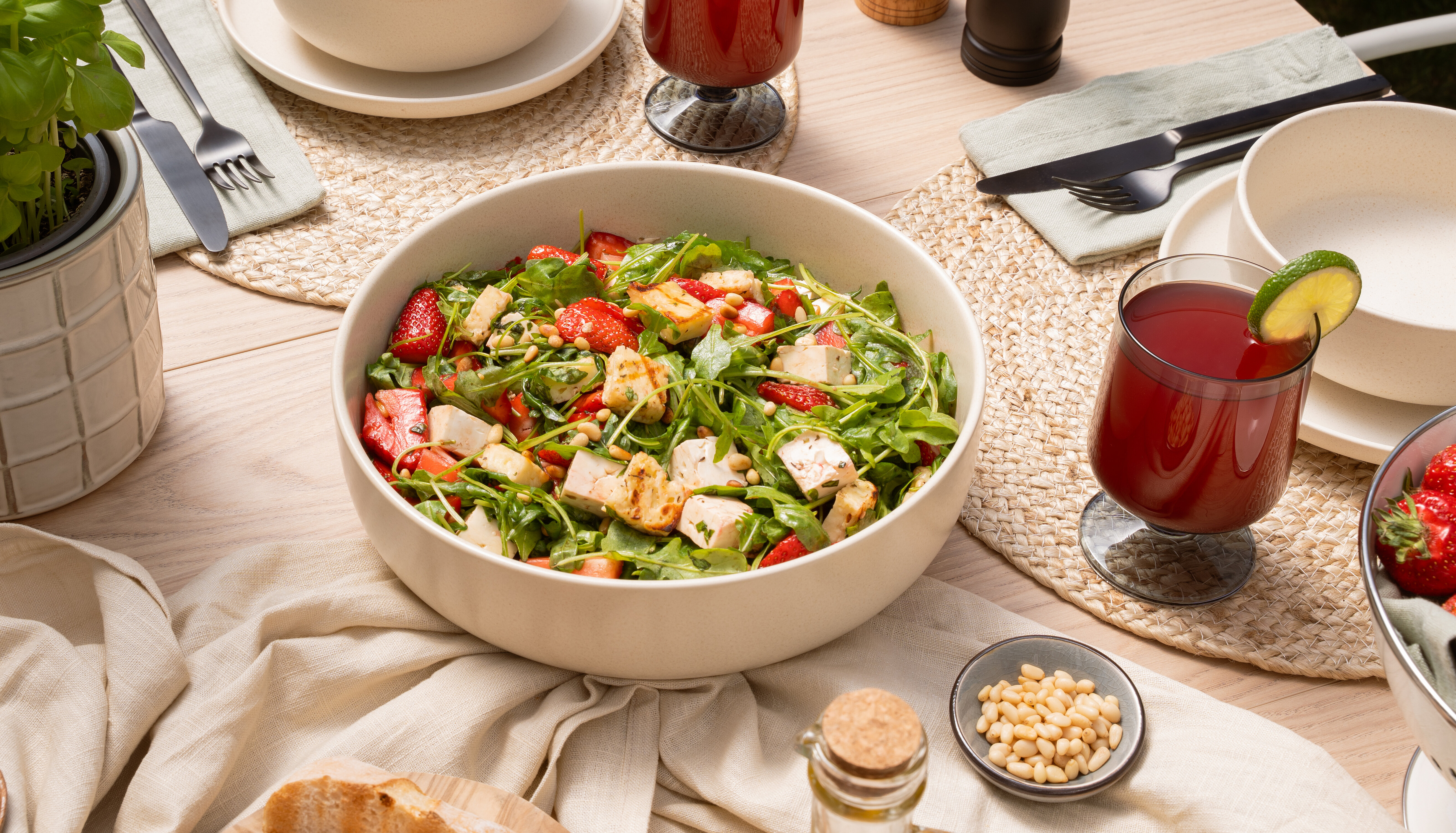 Sommerlich gedeckter Tisch mit Erdbeer-Rucola-Salat, gegrilltem Grillkäse, Hirtenkäse und frischen Erdbeeren.