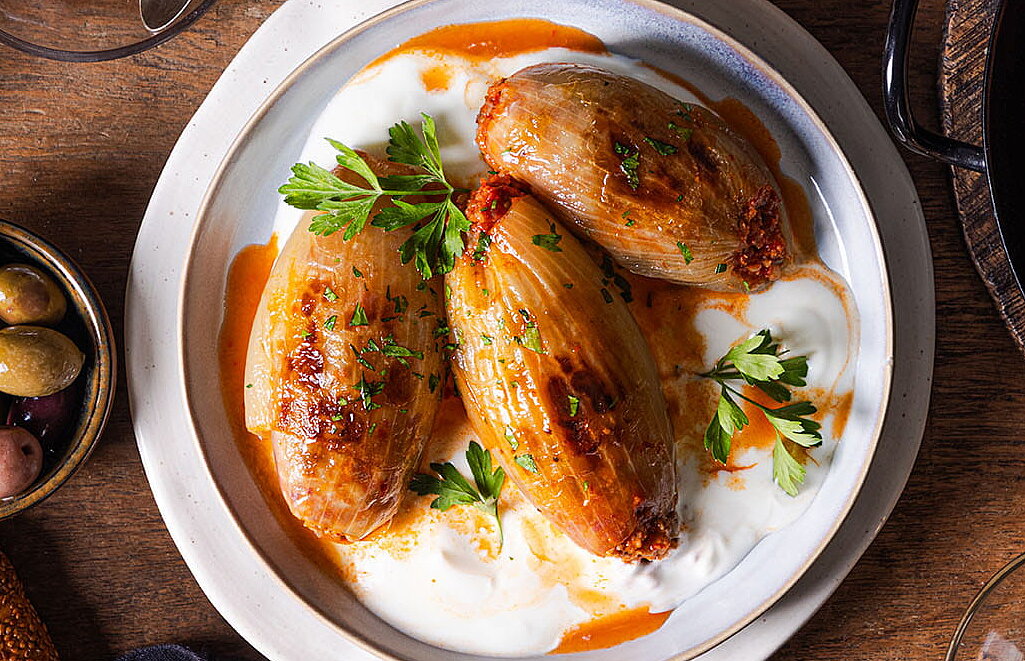 [Translate to Türkisch:] Gefüllte Zwiebeln (Soğan Dolması) mit Joghurt und Petersilie auf einem Teller