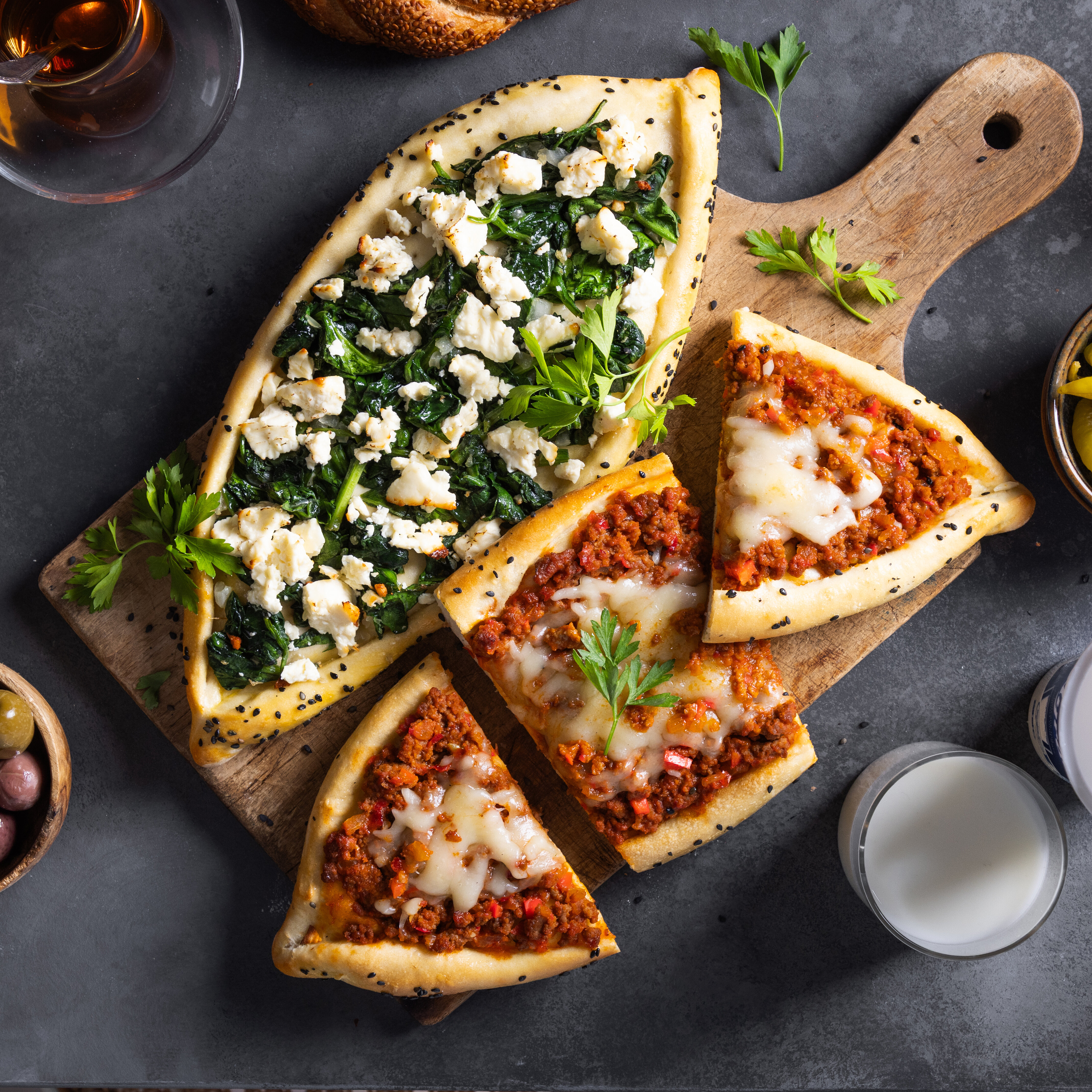 Türkische Pide mit Hackfleisch und Spinat, angerichtet auf einem Holzbrett