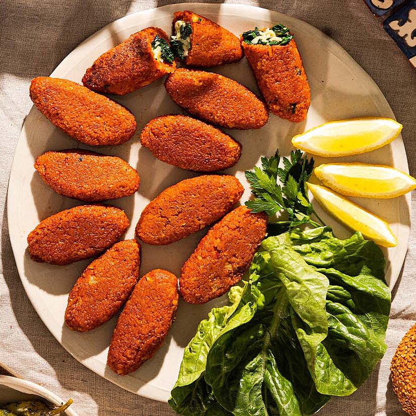 Köfte with kashkaval spinach filling fried until golden brown and served on a plate with spinach and lemons