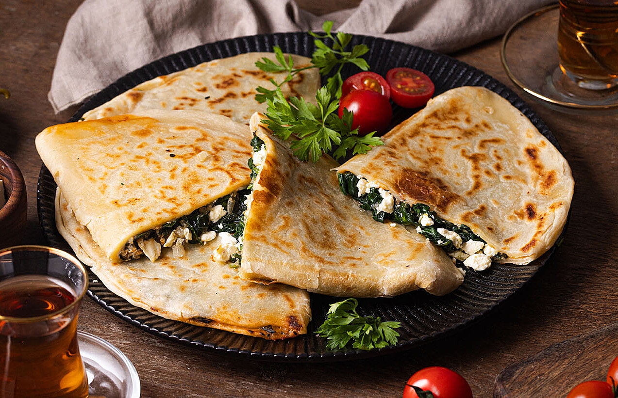 [Translate to Türkisch:] Türkische Gözleme mit Schafkäse und Kashkaval, goldbraun gebraten und auf einem Teller serviert