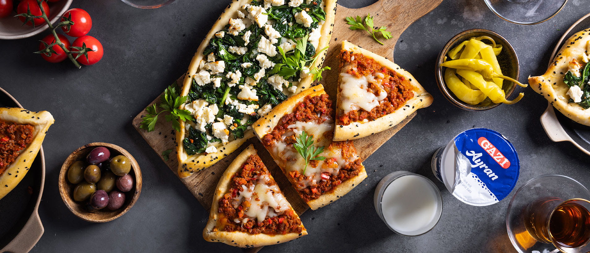 [Translate to Türkisch:] Türkische Pide mit Hackfleisch und Spinat, angerichtet auf einem Holzbrett