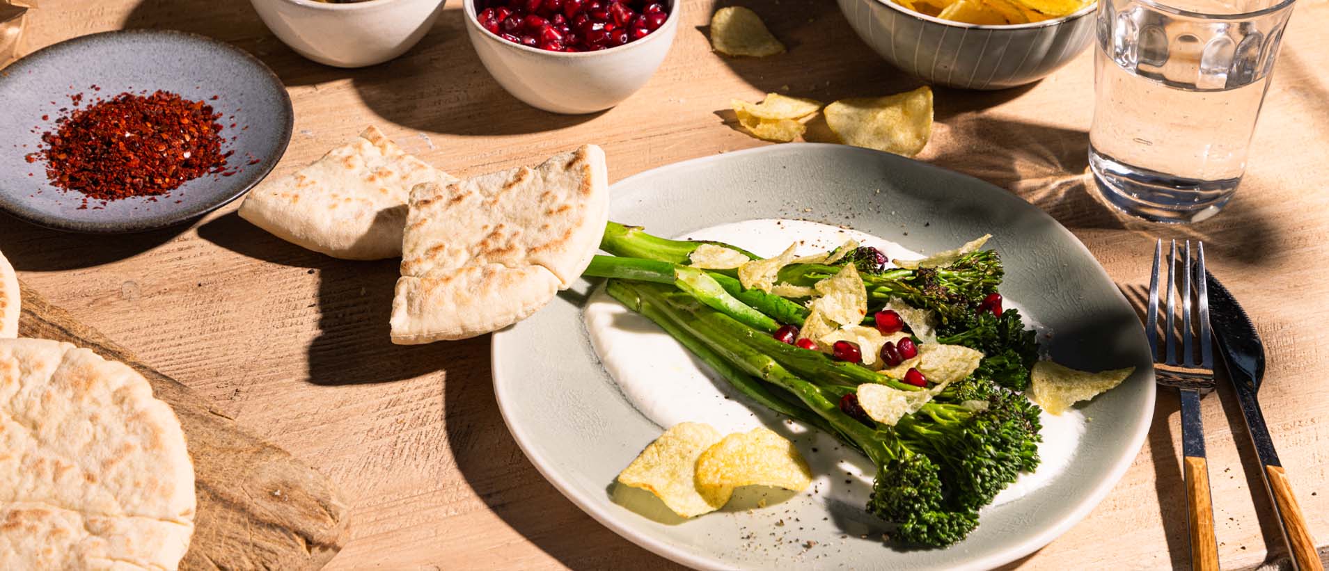Grilled broccoli on a creamy feta cream, sprinkled with a crunchy topping and garnished with pomegranate seeds.